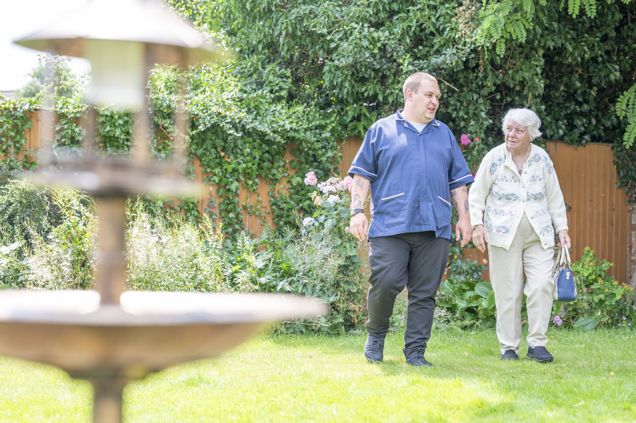 A resident walking with a team member in the garden