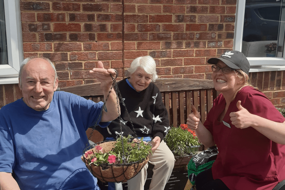 Resident and carer planting flower basket